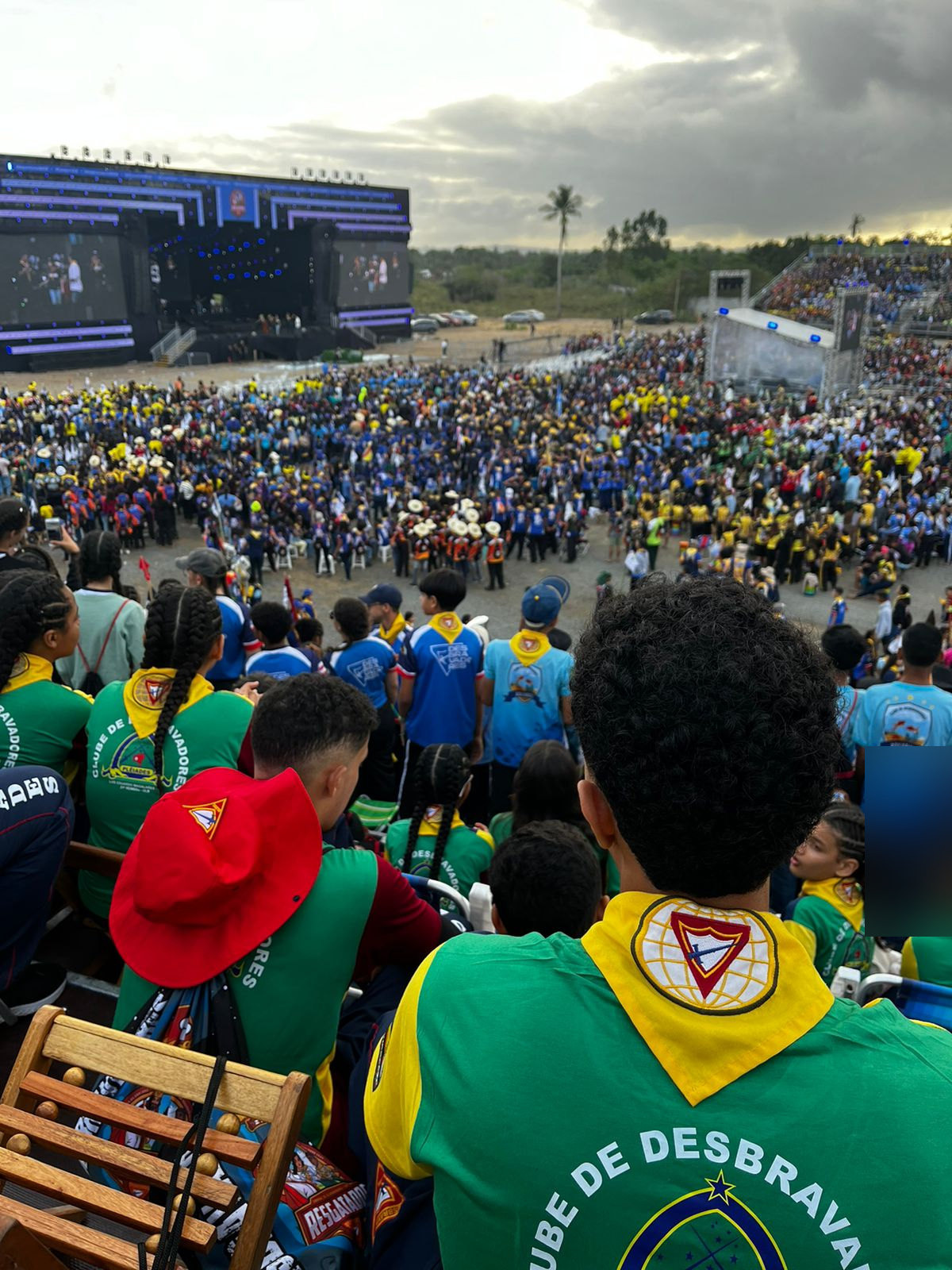 Desbravador do Plêiades de costas, com lenço amarelo, olhando a multidão do Campori